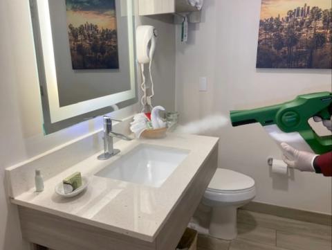 Disinfectant applied by electrostatic sprayer in guest bathroom