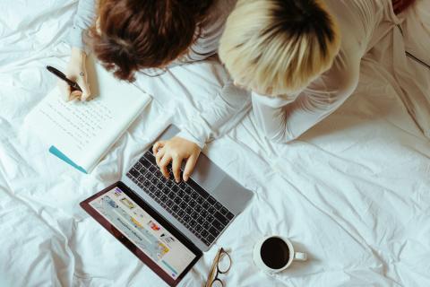 Mother and child doing online learning using laptop on a bed