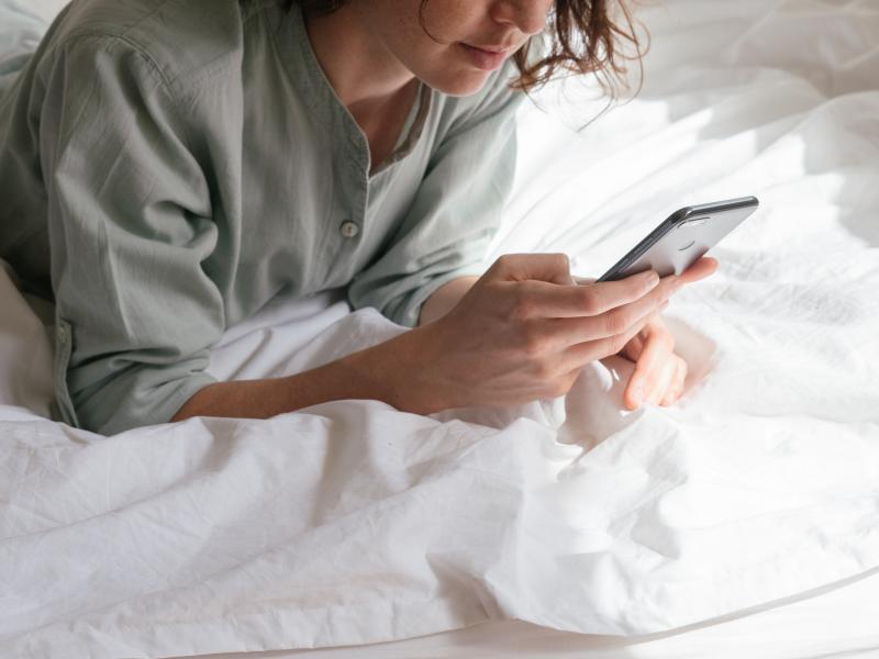 woman using smartphone in bed