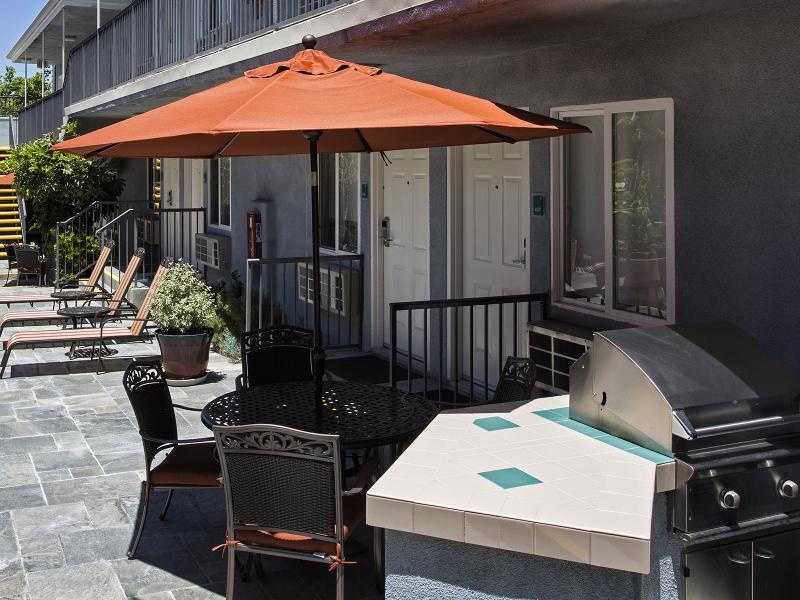 Patio Courtyard with gas BBQ, tables, chairs, umbrellas, and chaise lounges 